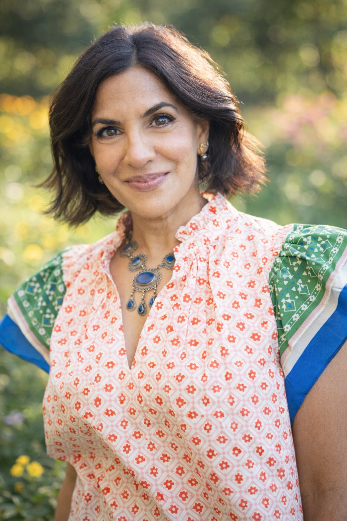 Woman wearing a floral blouse with a green and blue patterned sleeve outdoors.