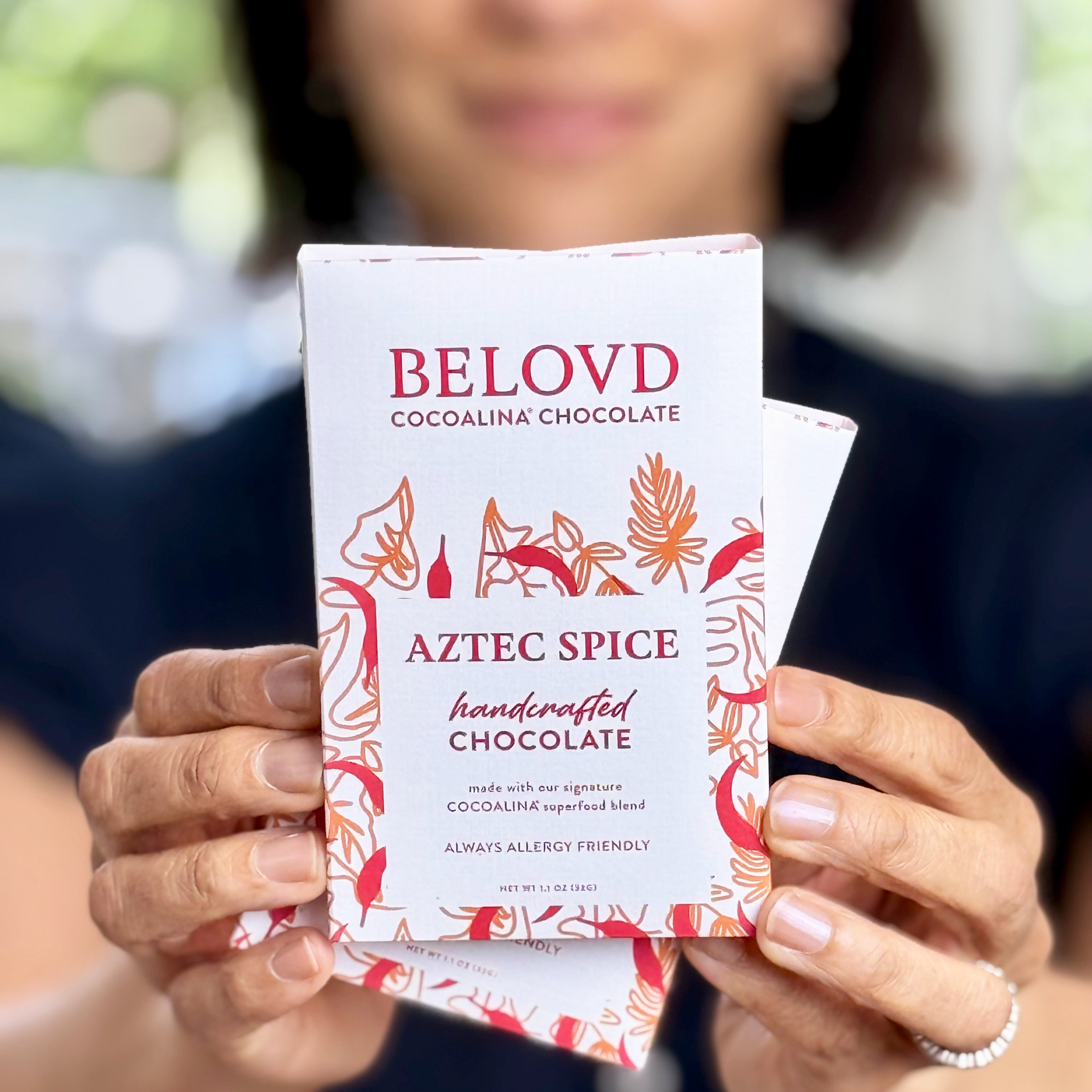 Hands holding Belovd Aztec Spice Chocolate Bar in packaging