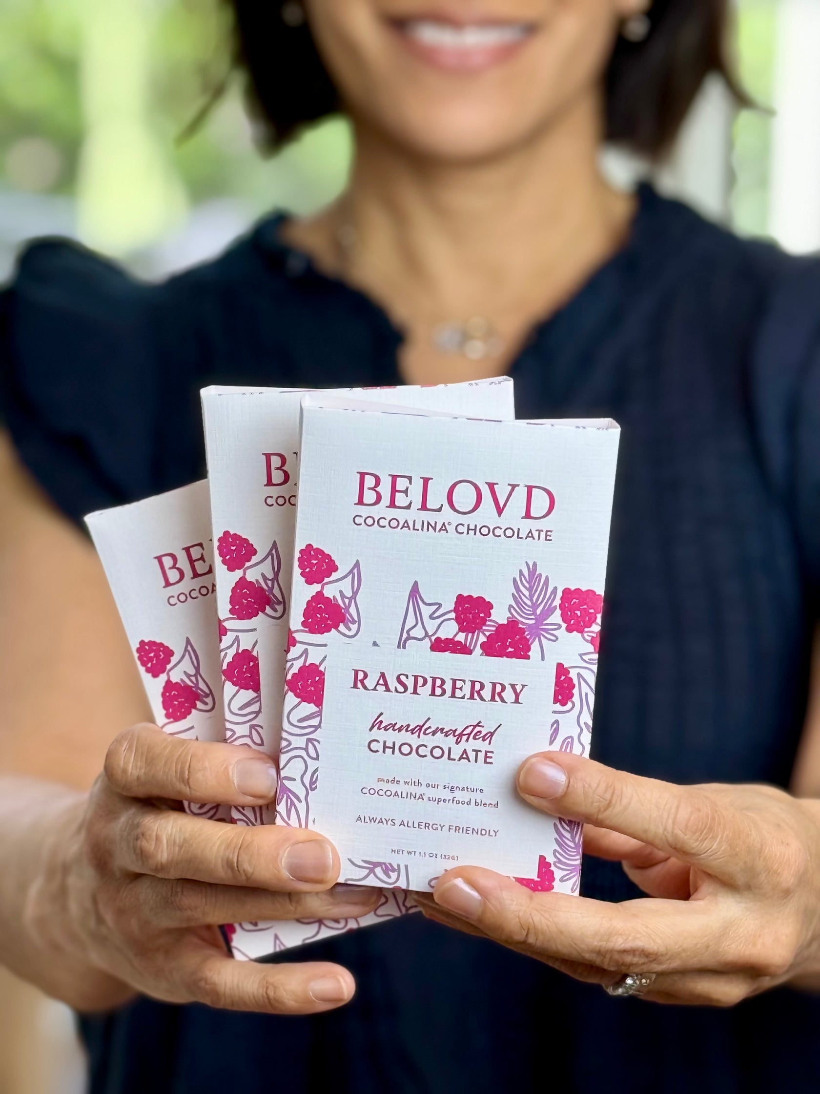 Woman holding three bars of Belovd Raspberry Chocolates in her hands