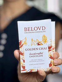 Hand holding Belovd Golden Chai Chocolate Bar in packaging
