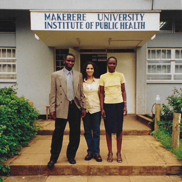 Priya Patil with two people standing in from of the Makere University Institute of Public Health in Uganda