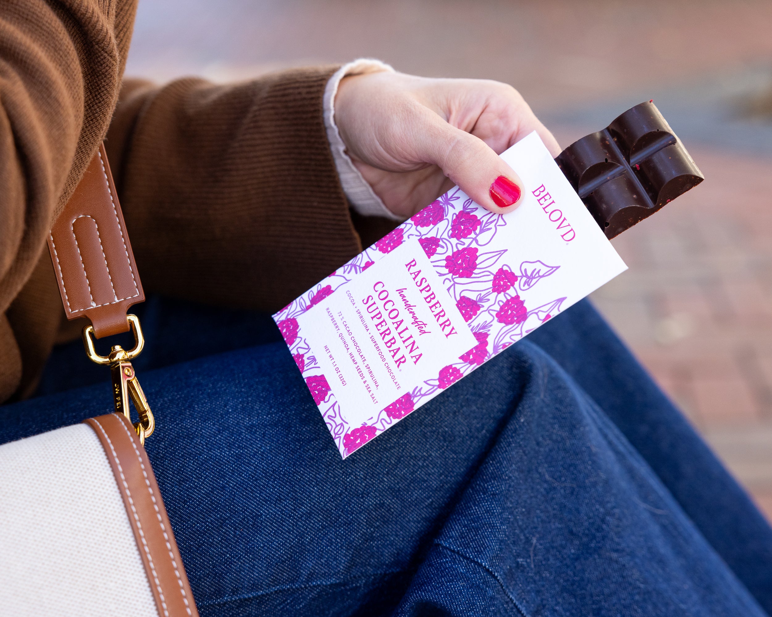 Person holding a raspberry chocolate bar and packaging with a blurred background